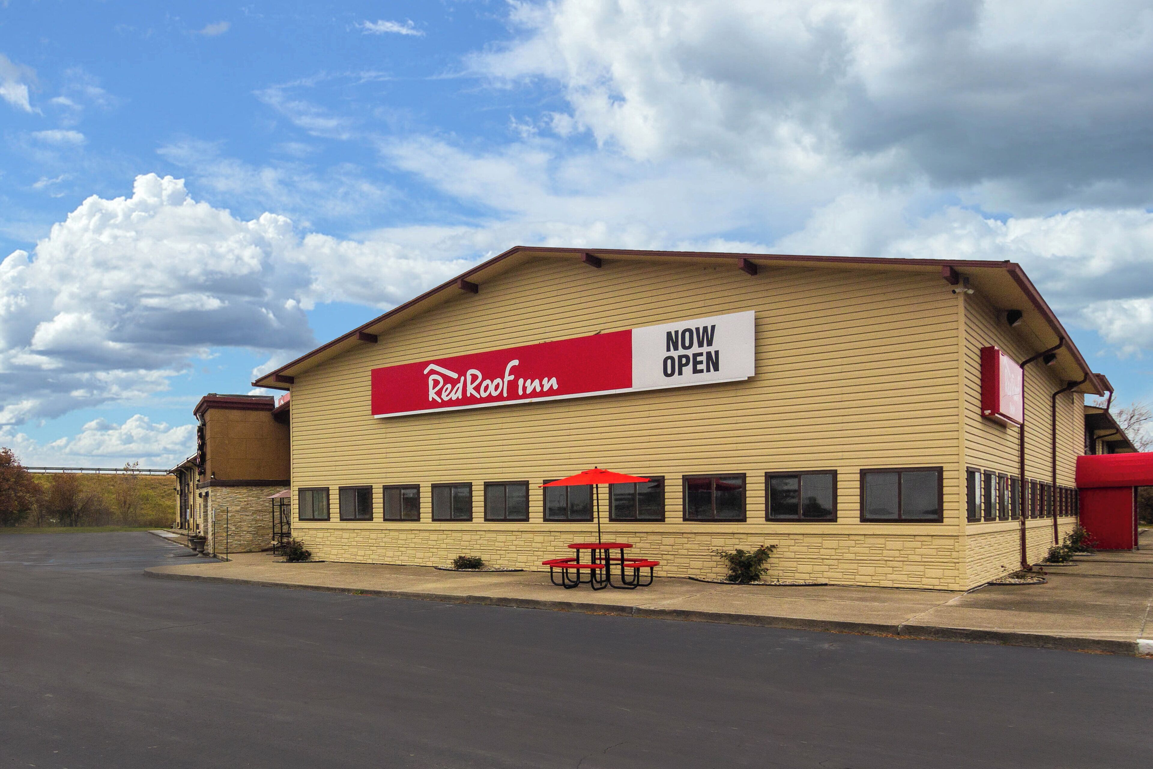A building with a sign that reads 'Now Open' and the name 'Reakool Inn' on a red banner.