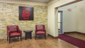A Red Roof Inn reception area with two leather chairs, a small table, and a stone wall. - Red Roof Inn Perrysburg (Perrysburg)