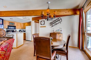 A dining area with a wooden ceiling, a chandelier, and a view of the kitchen in the background. - Ski-in/ski-out 2 Br - Sleeps 6 People 2 Bedroom Condo by RedAwning (Crested Butte)