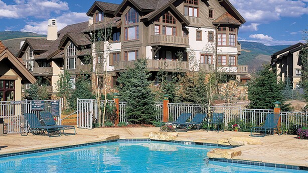A large building with multiple balconies and a swimming pool in front. - Elegant Updated 3 Bedroom Condo At One Arrowhead Place Condo by RedAwning (Edwards)