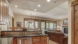 A spacious kitchen with a large island, wooden cabinets, and a stone fireplace. - Elegant Updated 3 Bedroom Condo At One Arrowhead Place Condo by RedAwning (Edwards)