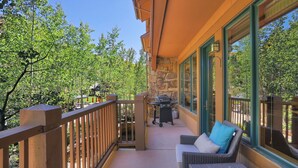 A balcony with wicker furniture, a grill, and a stone wall. - Elegant Updated 3 Bedroom Condo At One Arrowhead Place Condo by RedAwning (Edwards)