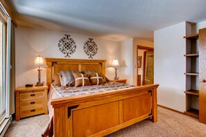 Cozy retreat with a large bed, bedside tables, and shelving.