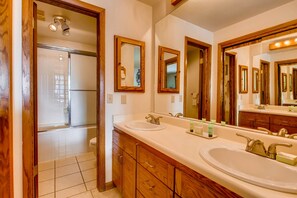 Bathroom features a sink, shower, and toilet, with a large mirror and vanity.