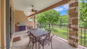 An outdoor patio with a stone pillar, a grill, and a table with chairs. - Riverview Terrace Rg 203 3 Bedroom Condo by RedAwning (New Braunfels)