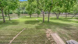 A park with grassy areas, trees, and a body of water. - Riverview Terrace Rg 203 3 Bedroom Condo by RedAwning (New Braunfels)