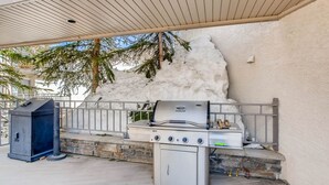 An outdoor grill area with a stone wall and a metal railing. - Unique & Modern 3 Br/2ba - Ski-in/ski-out 3 Bedroom Condo - No Cleaning Fee! by RedAwning (Crested Butte)