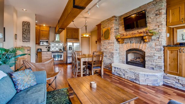 A spacious living area with a stone fireplace, wooden dining table, and a comfortable seating arrangement. - Unique & Modern 3 Br/2ba - Ski-in/ski-out 3 Bedroom Condo - No Cleaning Fee! by RedAwning (Crested Butte)