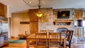 A modern kitchen with a stone fireplace, wooden dining table, and built-in appliances. - Unique & Modern 3 Br/2ba - Ski-in/ski-out 3 Bedroom Condo - No Cleaning Fee! by RedAwning (Crested Butte)