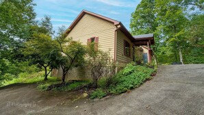 A single-story house with a gabled roof, surrounded by lush greenery and trees.