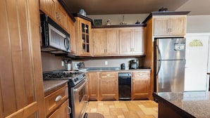 A kitchen with wooden cabinets, a stainless steel refrigerator, a dishwasher, and a stove. - Enchanted Primrose 2 Bedroom Chalet by RedAwning (Sevierville)