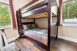 A bunk bed with a quilt, wooden flooring, and a window with a view of trees. - Enchanted Primrose 2 Bedroom Chalet by RedAwning (Sevierville)