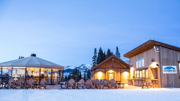 A wooden building with a sign reading "Umbrella Bar at Ten Peaks" and a covered seating area with chairs and tables. - 1 Br + Loft With Mountain Views 1 Bedroom Condo - No Cleaning Fee! by RedAwning (Crested Butte)