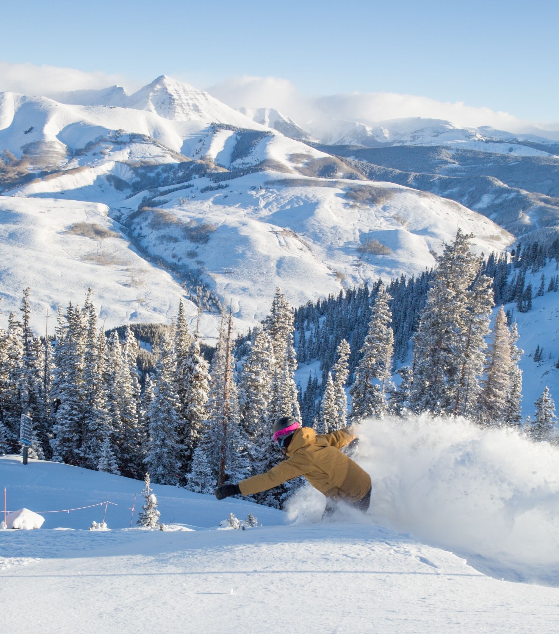 A snowy mountain landscape with a skier in motion.