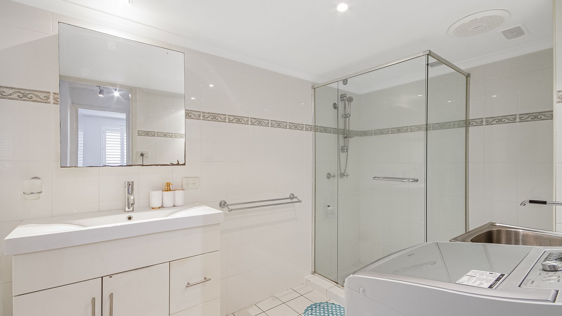 A modern bathroom with a glass-enclosed shower, a white sink with a vanity, and a large mirror.