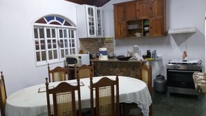 A compact kitchen with a dining area, featuring a stone countertop, a stove, and wooden cabinets. - Holiday home accommodation for up to 12 people (Cabo Frio)