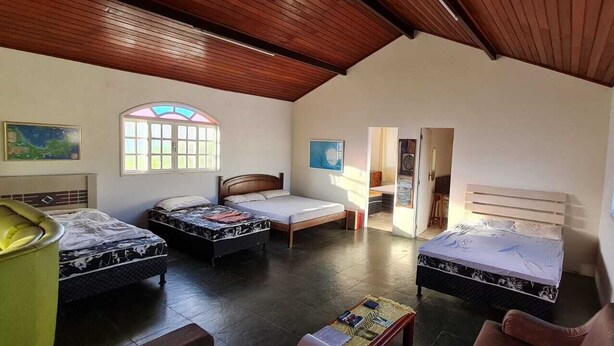 A room with three beds, a wooden ceiling, and a large window. - Holiday home accommodation for up to 12 people (Cabo Frio)