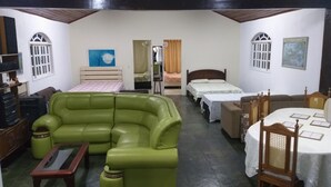 A room with a green sofa, two single beds, a wooden table, and a small TV. - Holiday home accommodation for up to 12 people (Cabo Frio)