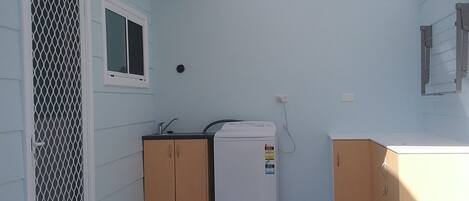 A compact laundry room with a washing machine, a dryer, and wooden cabinets.