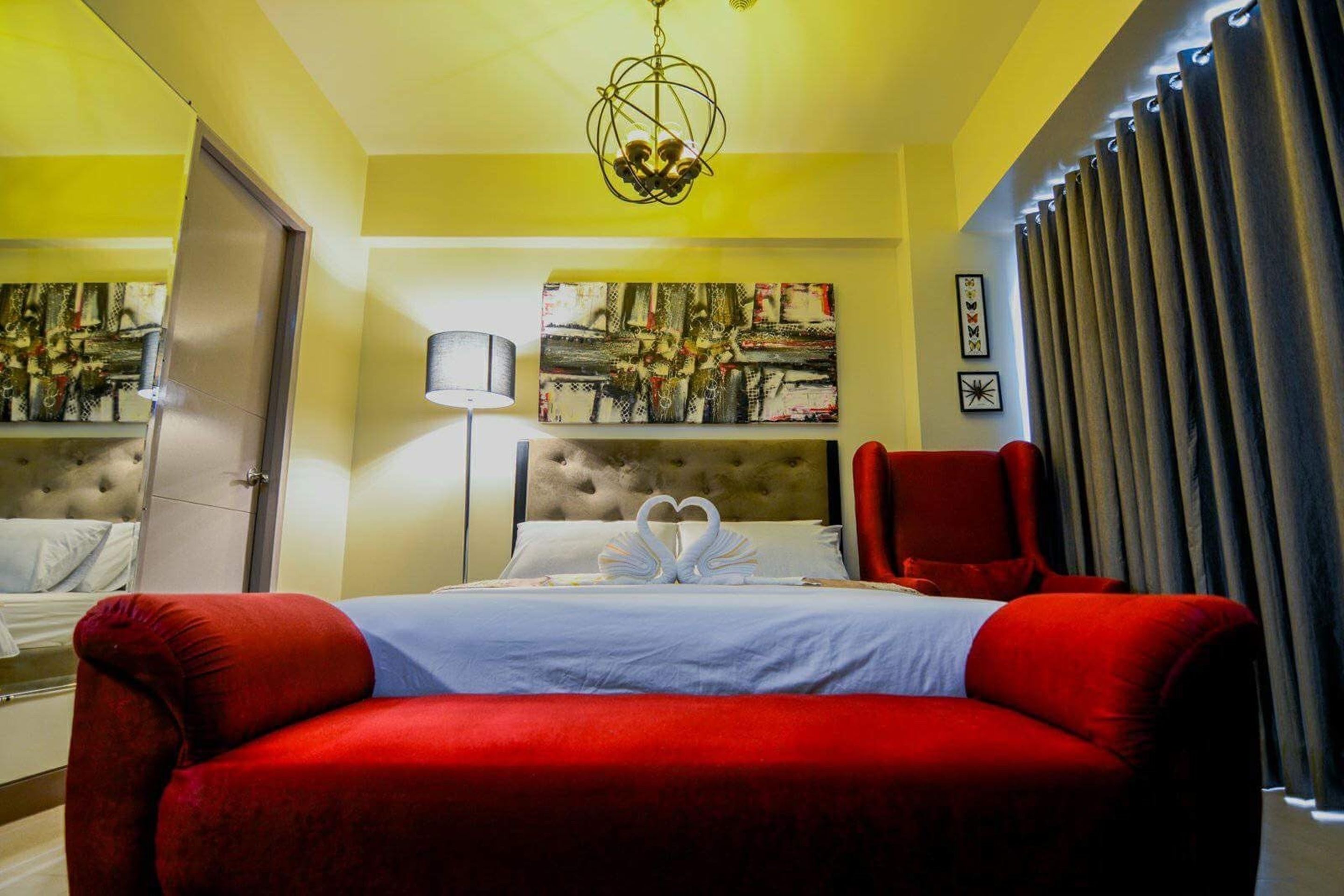 Ein Hotelzimmer mit einem roten Sofa, einem gesteppten Kopfteil, einem Bild an der Wand und einer Chandelier.