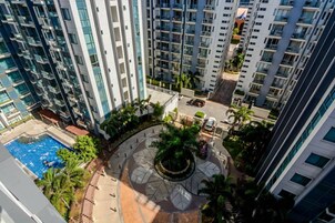 Un edificio residencial alto con múltiples balcones, un patio central con jardín circular y una piscina.