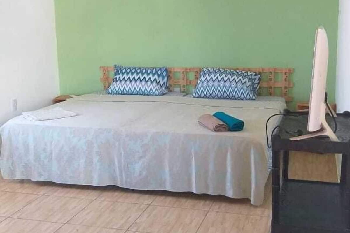 Une chambre à coucher avec un lit, des oreillers, un bureau et un appareil de climatisation.