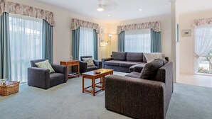 A spacious living room with two sofas, a coffee table, and a bookshelf. - Cosy Unit at 2-3 Wyndham in Cowes (Cowes)