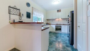 A compact kitchen with white cabinets, a built-in oven, a refrigerator, and a small countertop. - Cosy Unit at 2-3 Wyndham in Cowes (Cowes)