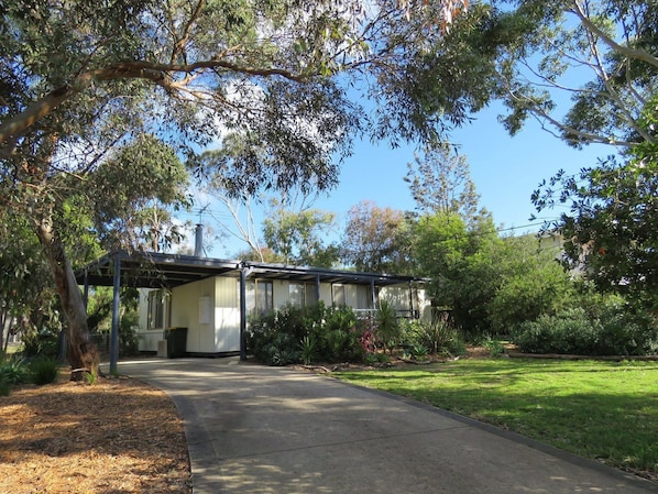 A house with a covered porch, surrounded by lush greenery and a well-maintained lawn.