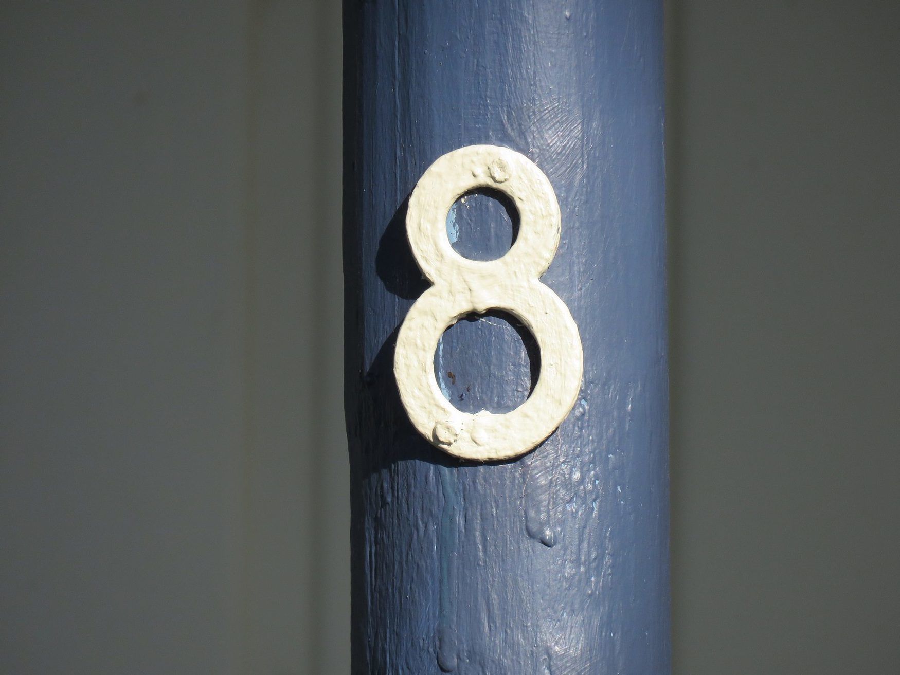 Primer plano del número 8 blanco sobre una superficie azul pintada.