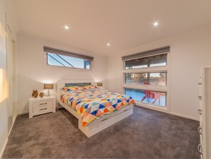 A bedroom with a bed, bedside tables, and a window with a view of a deck.