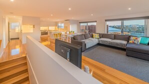A modern living room with a sectional sofa, a flat-screen TV, and a kitchen in the background. - 7 Boardwalk Lakeside in Cowes (Cowes)