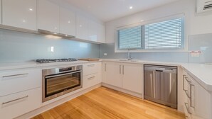 A modern kitchen with white cabinets, a stainless steel dishwasher, and an oven. - 7 Boardwalk Lakeside in Cowes (Cowes)