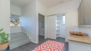 A clean, modern interior with a staircase, a patterned rug, and a small kitchen area. - 63 Marlin by Smiths Beach (Smiths Beach)