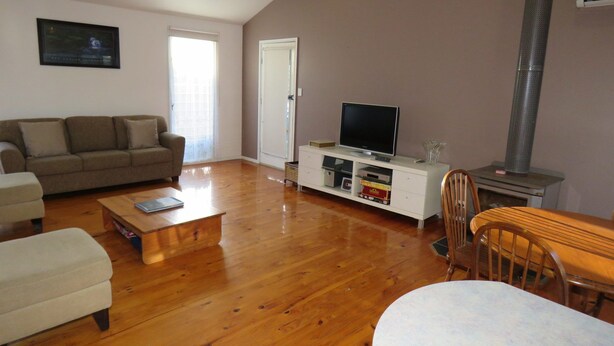 A living room with a sofa, coffee table, TV stand, and a fireplace. - 5 Little Penguin Cottage in Cowes (Cowes)