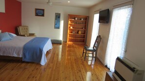A hotel room with a bed, a chair, a bookshelf, and a television. - 5 Little Penguin Cottage in Cowes (Cowes)