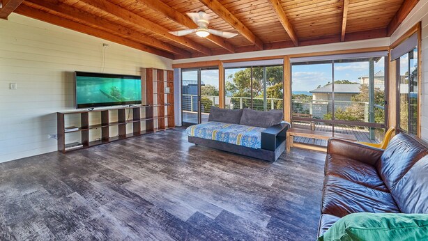 A spacious living area with a wooden ceiling, a large flat-screen TV, a sofa, and a bench. - 9 Boat Creek by the beach in Ventnor (Ventnor)