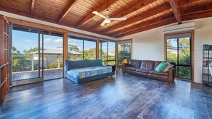 A spacious room with a large bed, a sofa, and a dining table. There are large windows providing a view of the outdoors. - 9 Boat Creek by the beach in Ventnor (Ventnor)