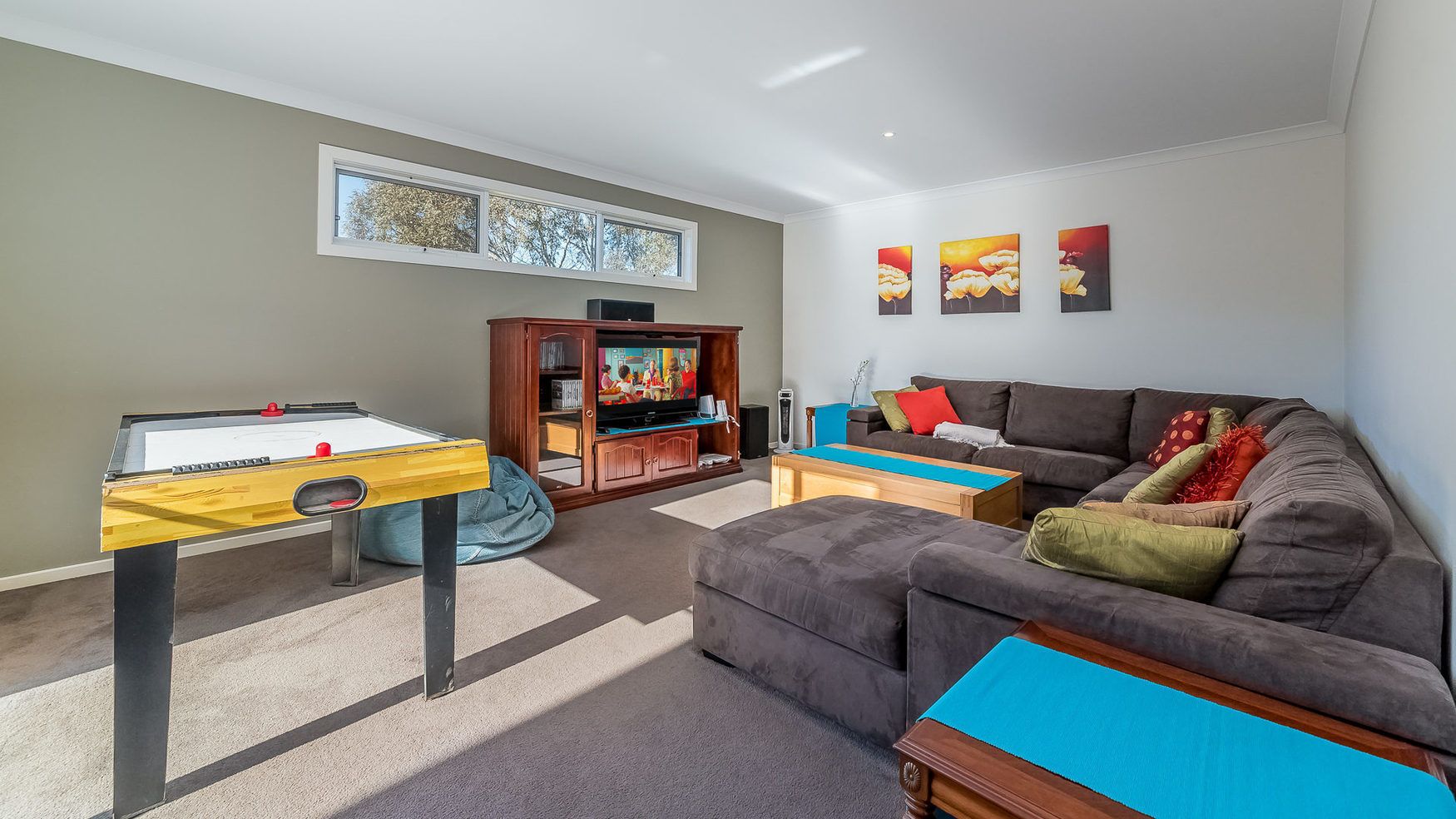 A living room with a foosball table, a sofa, a coffee table, and a TV stand.
