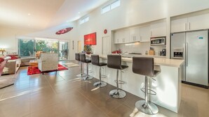 A modern kitchen with white cabinets, stainless steel appliances, and a central island with bar stools. - House on 37 Barramundi near Smiths (Smiths Beach)