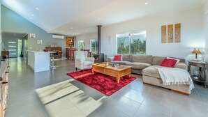A spacious living area with a fireplace, a sofa, a coffee table, and a red rug. - House on 37 Barramundi near Smiths (Smiths Beach)