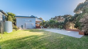 A residential property with a well-maintained lawn, a patio area, and a house with a blue roof. - House on 37 Barramundi near Smiths (Smiths Beach)