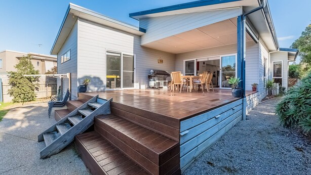 A modern house with a covered patio, a wooden deck, and a staircase leading to the entrance. - House on 37 Barramundi near Smiths (Smiths Beach)