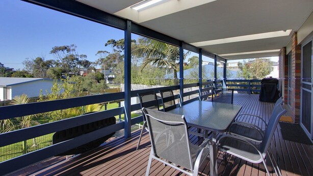 A covered outdoor area with a table and chairs, overlooking a body of water and greenery. - 47 Anderson with Pool in Cowes (Cowes)