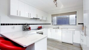 A modern kitchen with white cabinets, a stainless steel range, a coffee machine, and a window with a view. - 47 Anderson with Pool in Cowes (Cowes)