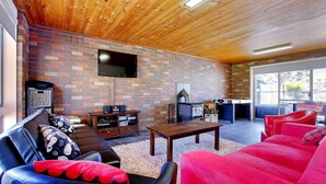 A cozy living room with a brick wall, a flat-screen TV, a fireplace, and comfortable seating. - 47 Anderson with Pool in Cowes (Cowes)