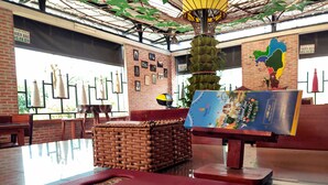 Een restaurant met een bakstenen muur, hangende lampen en een grote plant in het midden.
