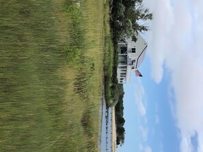 A coastal house with a porch, an American flag, and a view of the beach. - Chatham's Best Views-Harbor & Atlantic; On the Beach 4 Kayaks, 2 SUP's, 5 chairs (North Chatham)