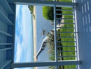 En overdækket terrasse med udsigt over en strand og en mole, der strækker sig ud i vandet.