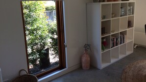 A room with a large window, a white bookshelf, and a potted plant. - Studio Rouge in heart of old Bowral only minutes walk to shops and restaurants (Bowral)